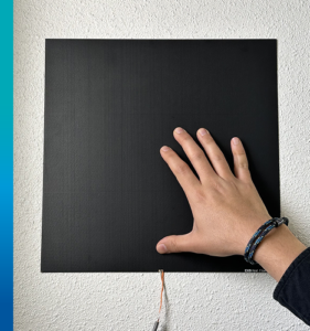 EKO HF-30S placed on the wall to measure and average heat flux perpendicular to the surface of the wall. The large size can be observed compared to the hand